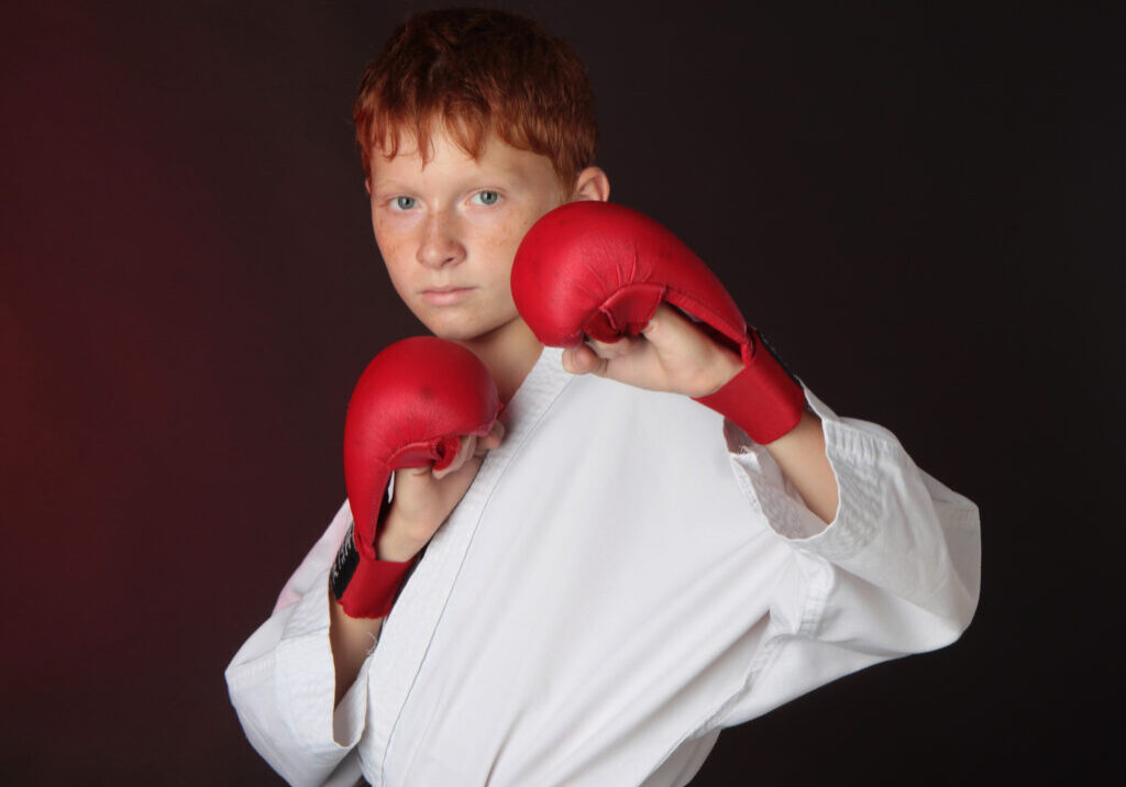 Teenager karate blue belt works off technique an attack while wearing gloves.